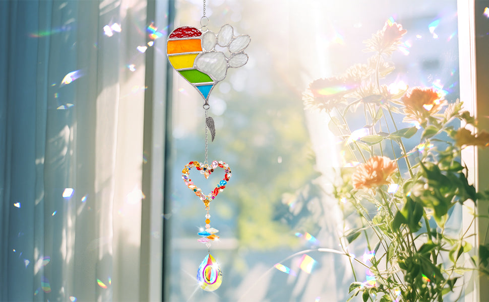 suncatcher metal rainbow paw and  heart-shaped rainbow pendant and teardrop crystal pendant hang on the windowsill under the sunshine